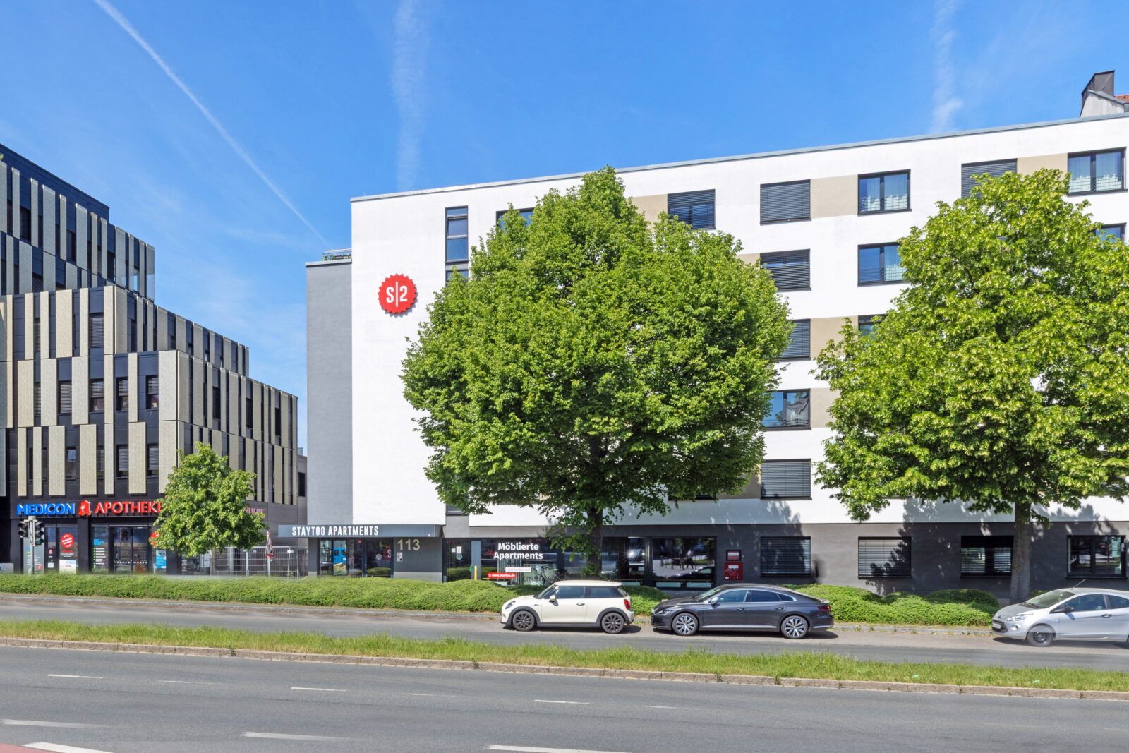Exterior view of the Staytoo Apartments Nuremberg building with main entrance, street view and parked cars in front.